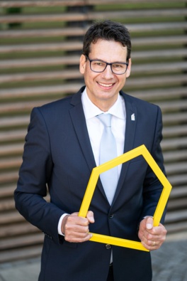 Adrian Köstler hält Kinderhilfe-Logo in der Hand